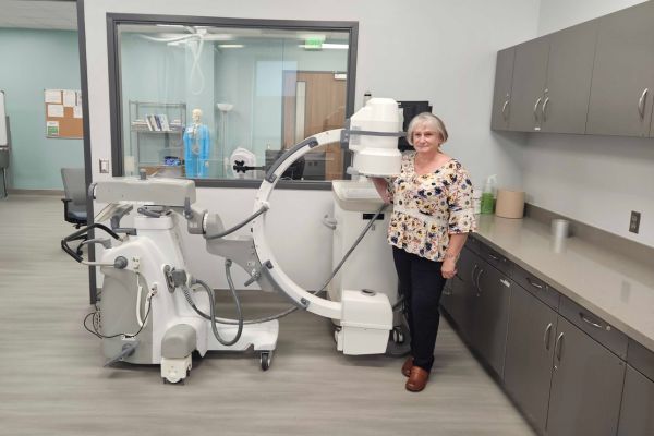 Professional standing by a Skanray C-arm X-ray machine in a modern medical imaging and procedure suite.