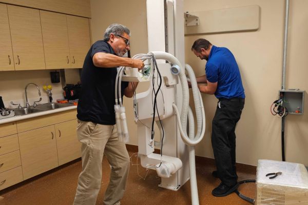 Technicians installing and wiring a medical X-ray imaging system in a healthcare facility.